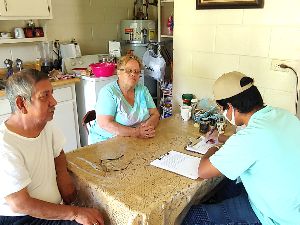 Photo of CCLP volunteer taking legal request in the home of farm workers on a labor camp